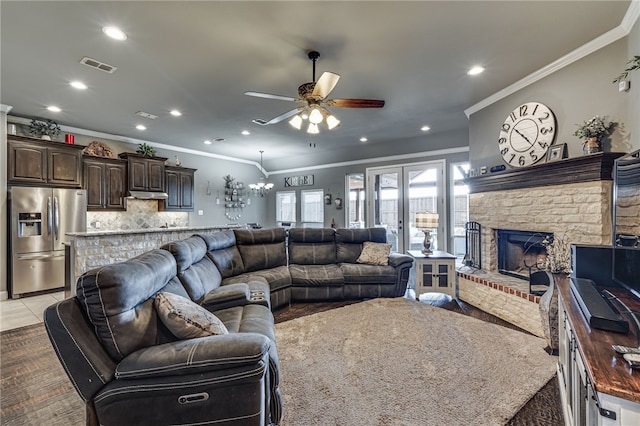 living room with crown molding, a fireplace, light tile patterned floors, and ceiling fan with notable chandelier