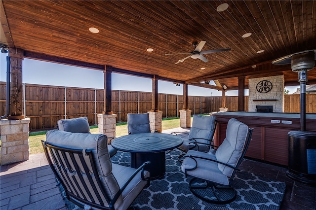 view of patio featuring ceiling fan and a large fireplace