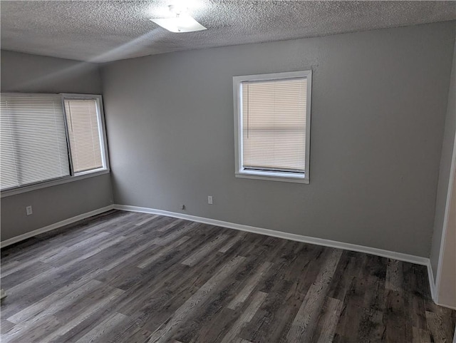 empty room with dark hardwood / wood-style floors and a textured ceiling