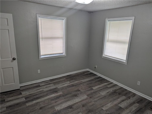 spare room with dark wood-type flooring and a textured ceiling