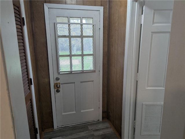 doorway to outside with wood walls and dark wood-type flooring