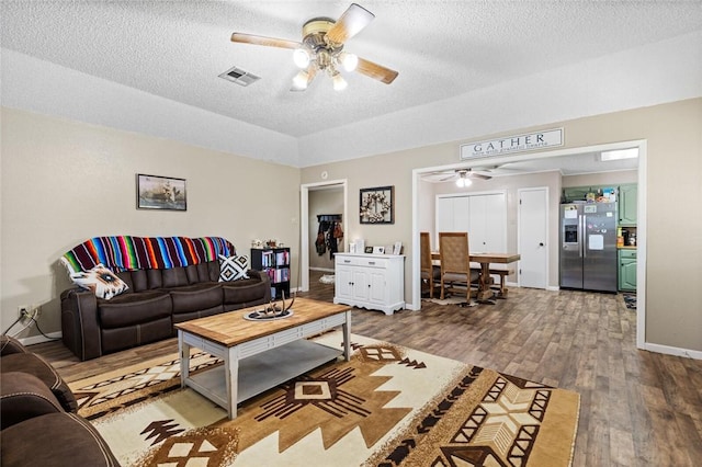 living room featuring wood-type flooring, a textured ceiling, and ceiling fan