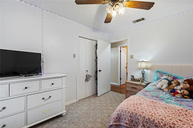 carpeted bedroom featuring a textured ceiling, a closet, and ceiling fan