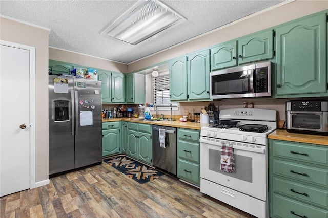 kitchen featuring appliances with stainless steel finishes, dark hardwood / wood-style flooring, crown molding, and sink