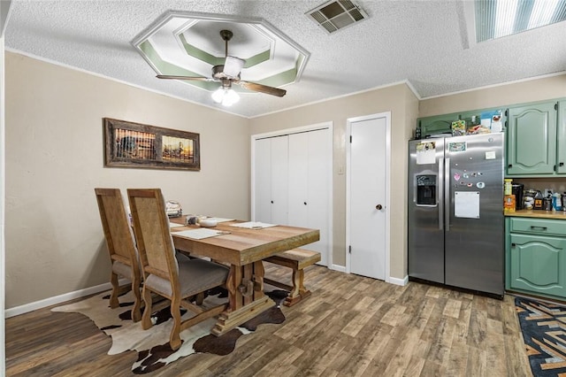 dining space with hardwood / wood-style floors, a textured ceiling, ceiling fan, and crown molding