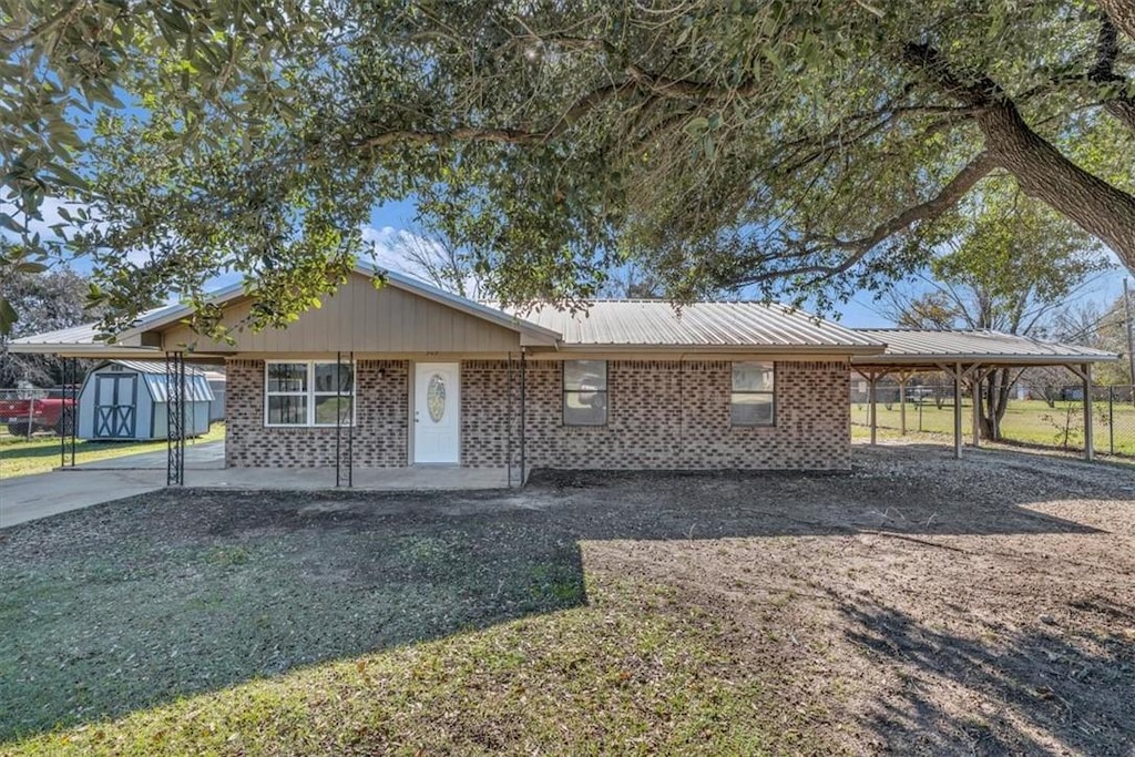 view of front of property featuring a carport and a storage shed