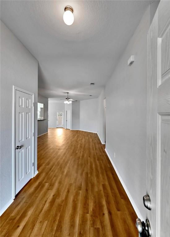 hallway with a textured ceiling and dark wood-type flooring