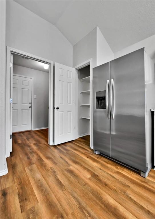 kitchen with stainless steel fridge with ice dispenser, vaulted ceiling, and hardwood / wood-style floors