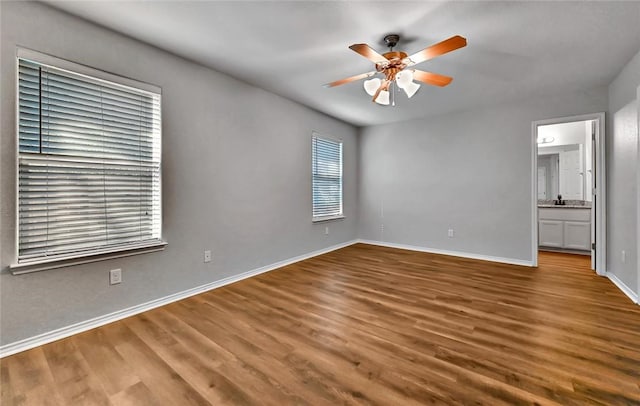 unfurnished bedroom featuring ceiling fan, hardwood / wood-style floors, ensuite bathroom, and sink