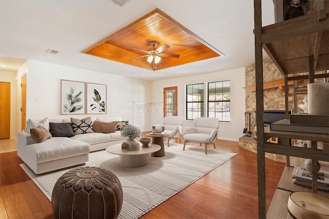 living room featuring a raised ceiling, ceiling fan, hardwood / wood-style floors, and wood ceiling