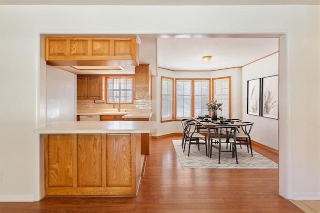 kitchen featuring sink, backsplash, light hardwood / wood-style floors, and kitchen peninsula