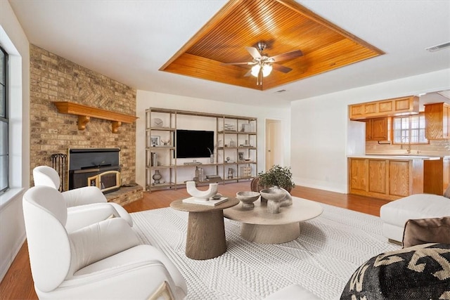 living room featuring sink, wood ceiling, light hardwood / wood-style floors, and a raised ceiling