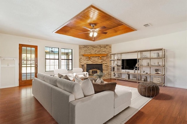 living room with a raised ceiling, ceiling fan, hardwood / wood-style floors, and wood ceiling