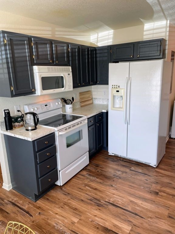 kitchen featuring dark hardwood / wood-style flooring, white appliances, and a textured ceiling