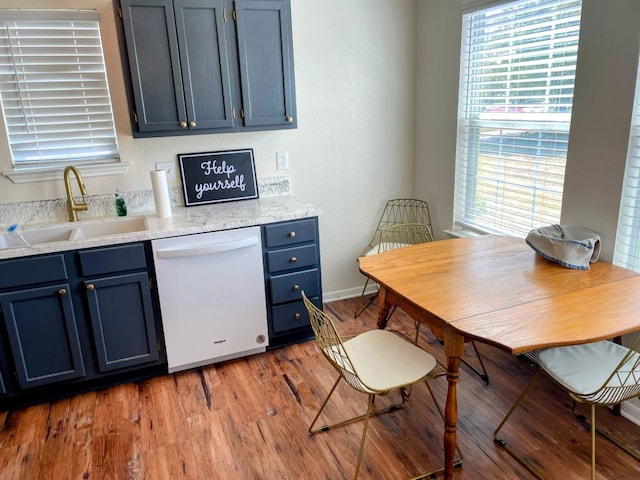 kitchen featuring blue cabinetry, dishwasher, sink, and light hardwood / wood-style flooring