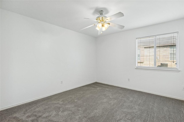 spare room featuring dark carpet and ceiling fan