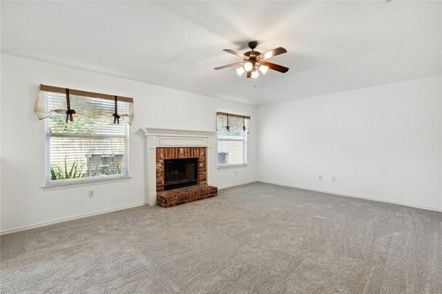 unfurnished living room with carpet floors, a brick fireplace, and ceiling fan