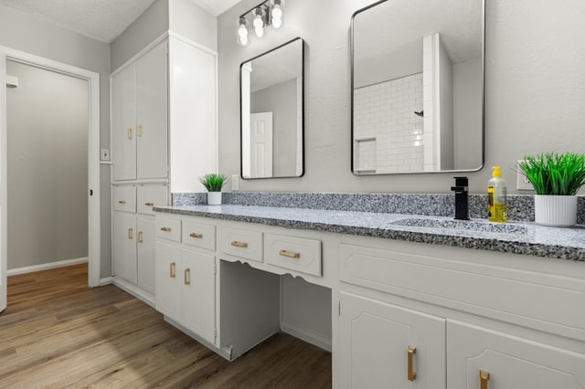 bathroom with wood-type flooring, vanity, and a textured ceiling