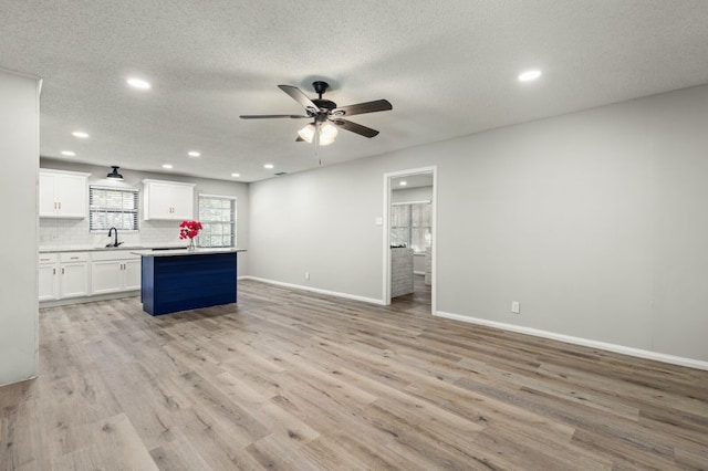 kitchen with white cabinets, light hardwood / wood-style floors, a textured ceiling, and a kitchen island