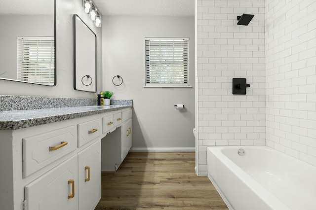 bathroom with hardwood / wood-style floors, vanity, a textured ceiling, and tiled shower / bath combo