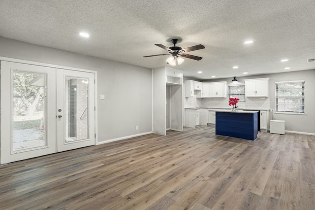 kitchen with a center island, white cabinetry, light hardwood / wood-style flooring, and french doors