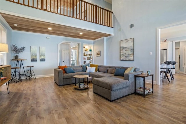 living area featuring visible vents, crown molding, baseboards, and wood finished floors