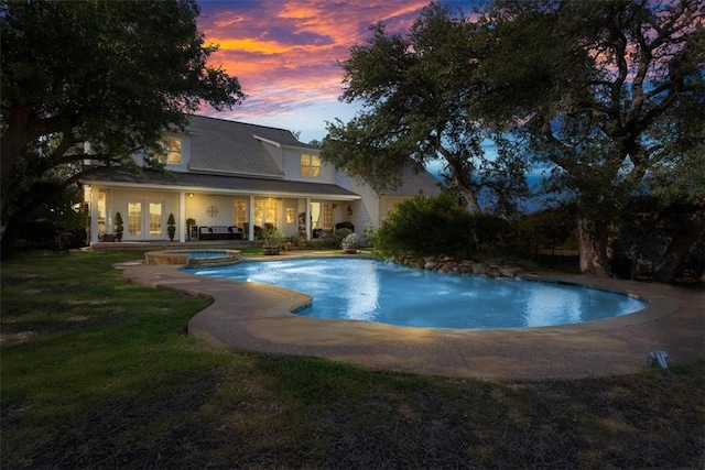 view of pool with french doors, a yard, a patio area, and a pool with connected hot tub