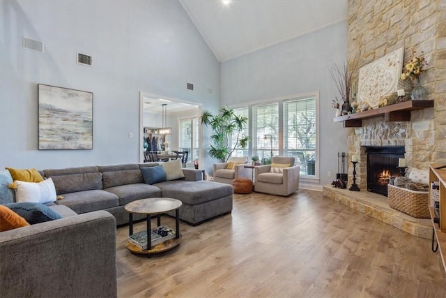 living area with visible vents, a stone fireplace, and wood finished floors