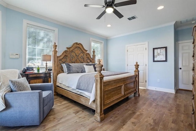 bedroom featuring ornamental molding, wood finished floors, visible vents, and baseboards