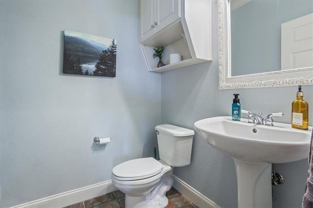 bathroom featuring toilet, baseboards, and a sink