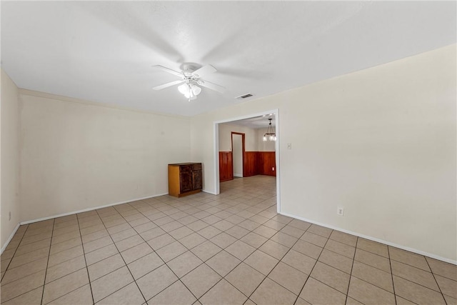 tiled empty room featuring ceiling fan with notable chandelier