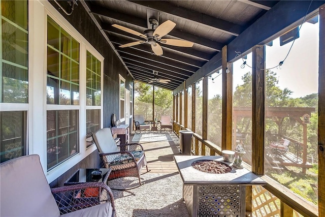 sunroom / solarium with lofted ceiling with beams, ceiling fan, and wooden ceiling