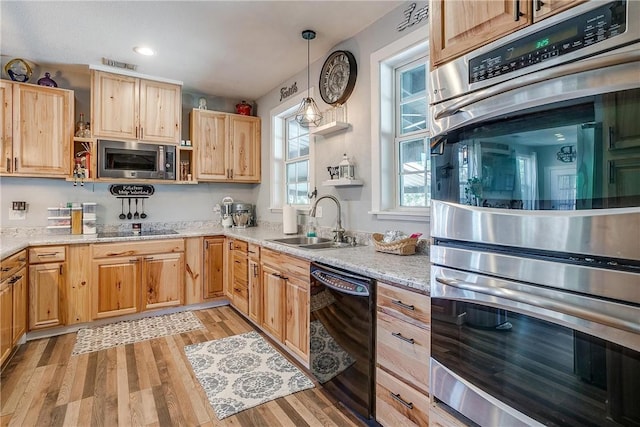 kitchen featuring light wood-type flooring, light stone counters, sink, black appliances, and hanging light fixtures