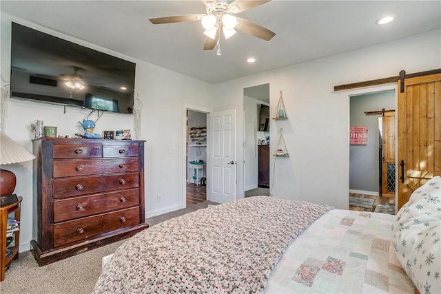 bedroom featuring ceiling fan, a barn door, and carpet floors