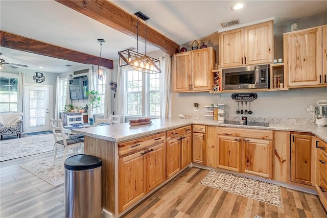 kitchen with beam ceiling, stainless steel microwave, light hardwood / wood-style flooring, kitchen peninsula, and decorative light fixtures