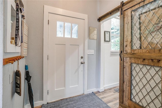 foyer entrance featuring a barn door and light hardwood / wood-style flooring