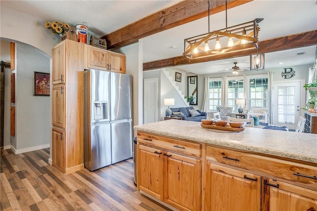 kitchen featuring stainless steel fridge, light wood-type flooring, ceiling fan, beamed ceiling, and hanging light fixtures