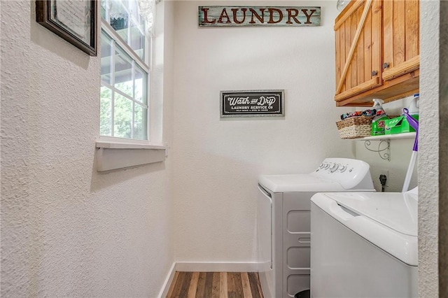 clothes washing area featuring cabinets, wood-type flooring, and washer and clothes dryer