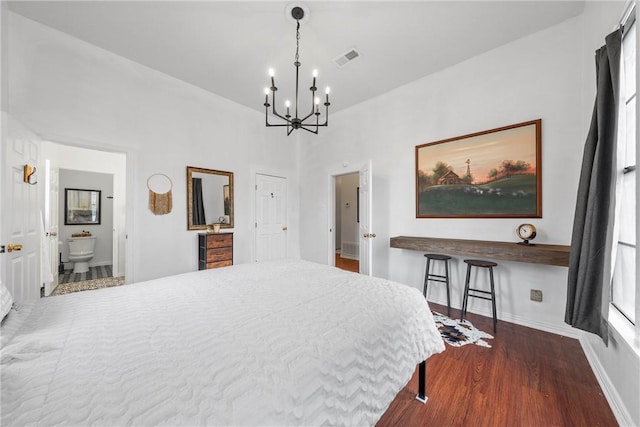 bedroom with connected bathroom, dark hardwood / wood-style flooring, and an inviting chandelier