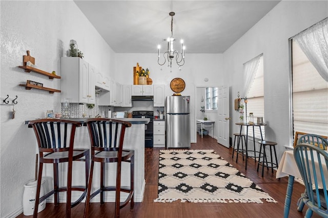 kitchen featuring white cabinetry, a kitchen breakfast bar, stainless steel fridge, kitchen peninsula, and electric range