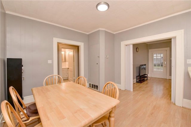 dining area with light hardwood / wood-style floors and crown molding