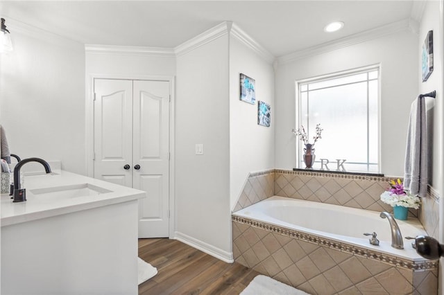 bathroom with wood-type flooring, vanity, tiled bath, and crown molding