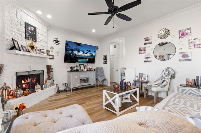 living room with hardwood / wood-style floors, a fireplace, ceiling fan, and crown molding