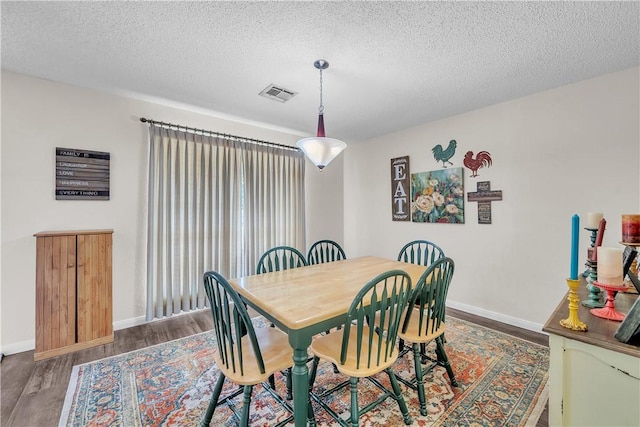 dining space featuring a textured ceiling and dark wood-type flooring