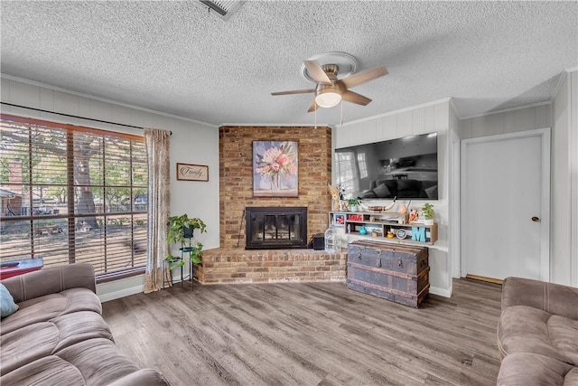 living room featuring a fireplace, wood-type flooring, ceiling fan, and ornamental molding