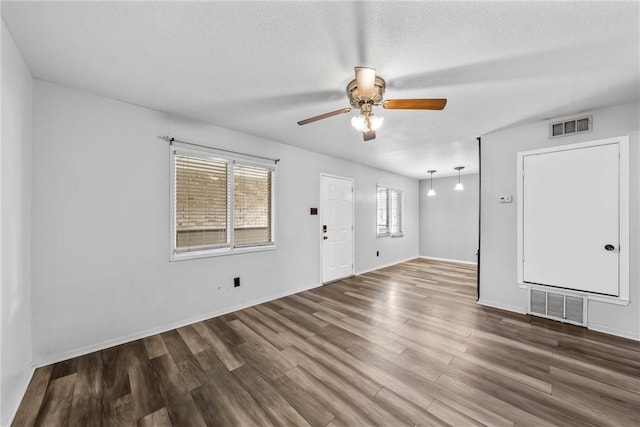 unfurnished room with a textured ceiling, ceiling fan, and dark hardwood / wood-style floors