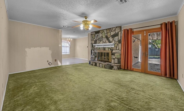 unfurnished living room with french doors, a stone fireplace, a textured ceiling, carpet, and ceiling fan with notable chandelier