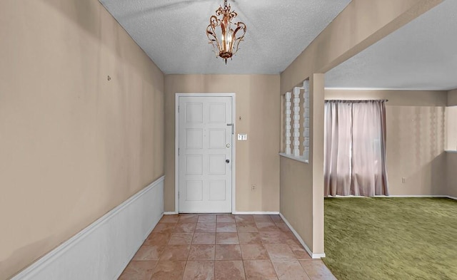 carpeted foyer featuring a chandelier and a textured ceiling