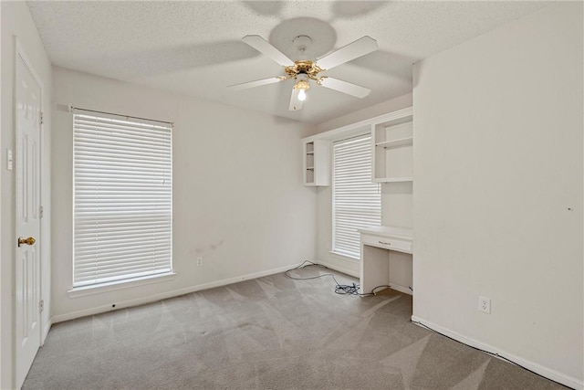 unfurnished bedroom featuring multiple windows, a textured ceiling, light colored carpet, and ceiling fan