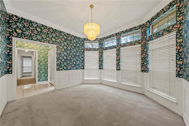 empty room with ornamental molding, a chandelier, light carpet, and a textured ceiling